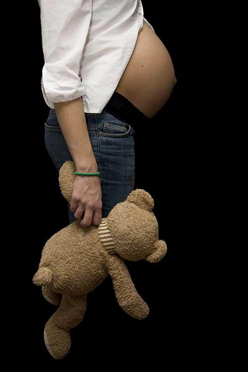 pregnant young woman showing her belly, holding a teddy bear