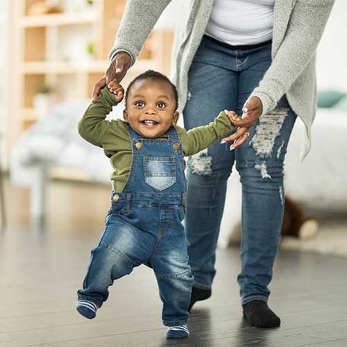 Woman teaching small child to walk